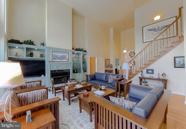 living room with stairway, wood finished floors, a high ceiling, and a premium fireplace