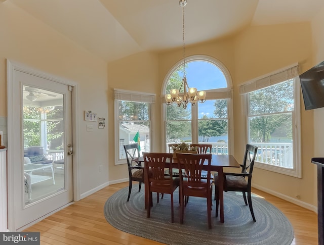 dining room featuring lofted ceiling, a notable chandelier, baseboards, and light wood-type flooring