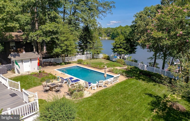 view of swimming pool with an outbuilding, a patio, a shed, a fenced backyard, and a water view