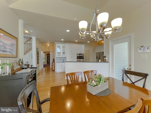 dining area with stairway, ornate columns, light wood-style flooring, recessed lighting, and a notable chandelier