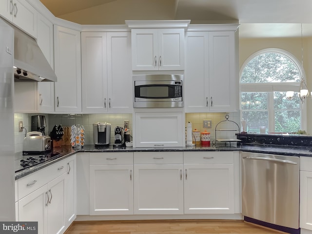 kitchen with dark stone countertops, white cabinets, tasteful backsplash, and appliances with stainless steel finishes