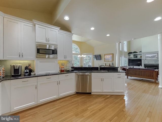 kitchen with lofted ceiling, a sink, decorative backsplash, stainless steel appliances, and white cabinets