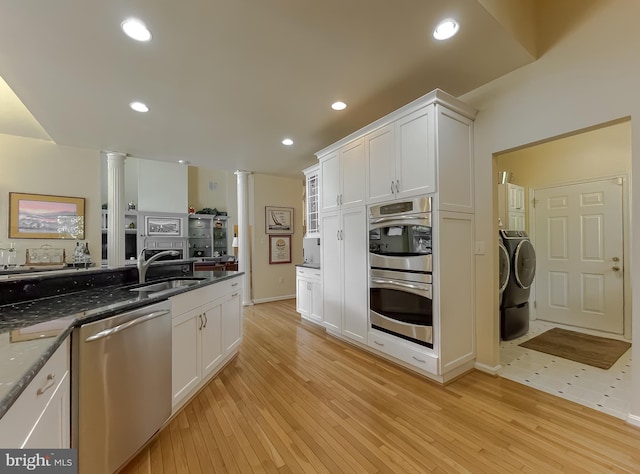 kitchen featuring white cabinetry, decorative columns, a sink, appliances with stainless steel finishes, and washer and dryer