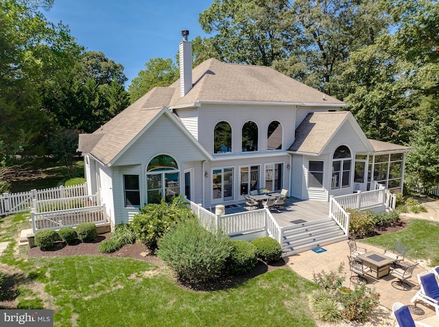 rear view of house with a patio, fence, a sunroom, a chimney, and a fire pit