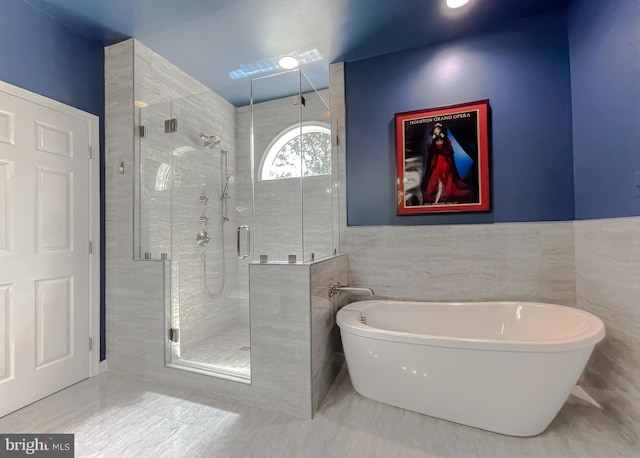 bathroom with a soaking tub, tile walls, and a shower stall