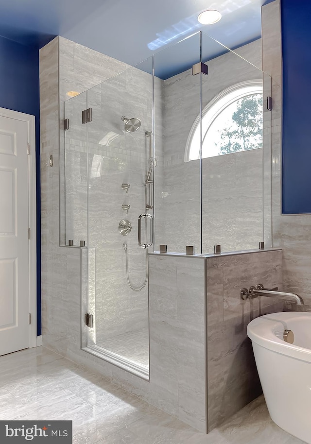 bathroom with a stall shower, tile walls, and a freestanding tub