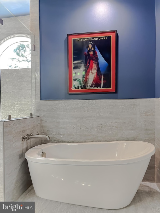 bathroom featuring a soaking tub and tile walls