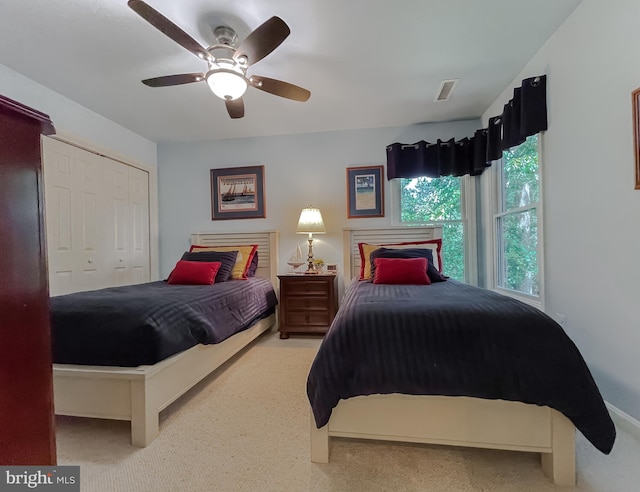 carpeted bedroom with a closet, visible vents, and ceiling fan