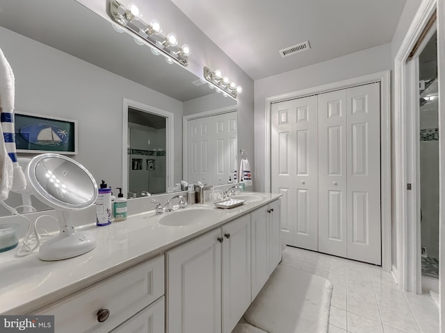 full bath with visible vents, a sink, a shower stall, tile patterned flooring, and double vanity