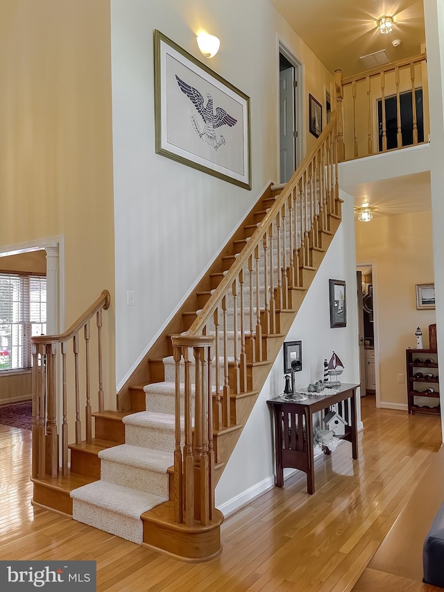 stairs with baseboards, a towering ceiling, and wood-type flooring