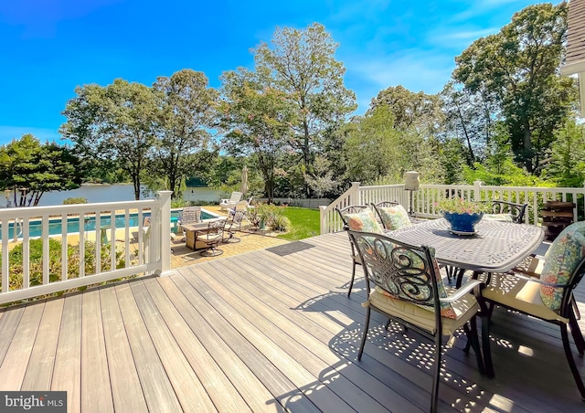 wooden terrace with a fenced in pool, outdoor dining area, and a water view