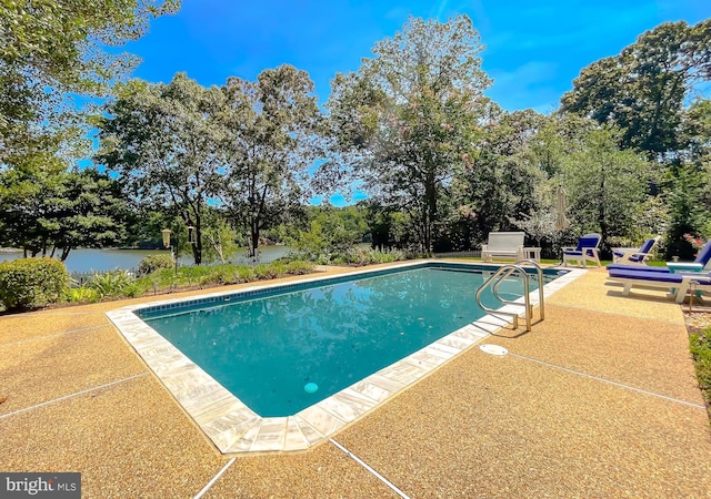 pool featuring a water view and a patio area