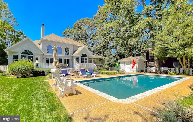 view of pool featuring a fenced in pool, fence, an outdoor structure, a patio area, and a lawn