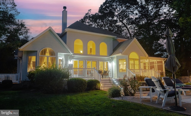 rear view of property featuring a porch, a chimney, and a patio