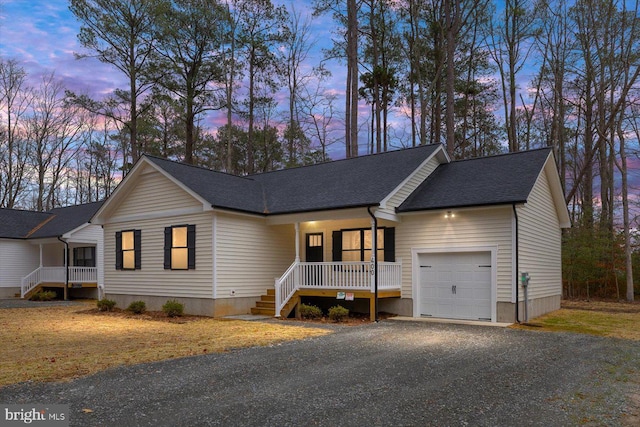 view of front facade with a shingled roof, covered porch, driveway, and an attached garage