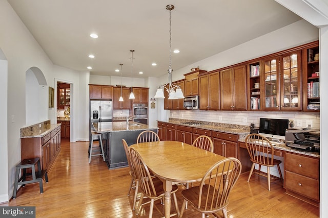 dining space featuring recessed lighting, arched walkways, built in study area, and light wood finished floors