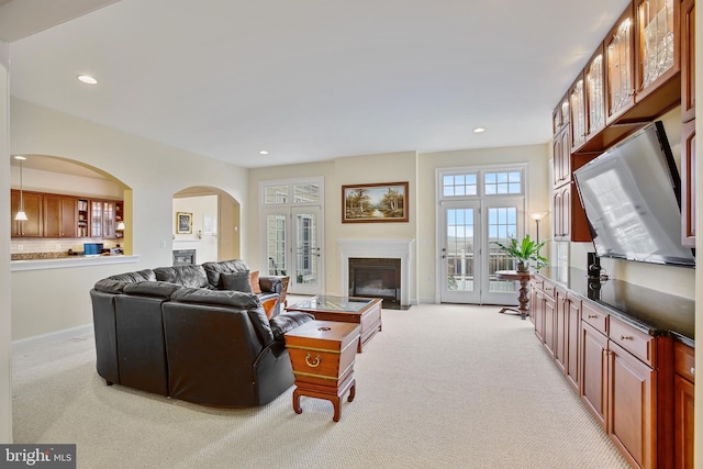 living area featuring recessed lighting, baseboards, light colored carpet, and a glass covered fireplace