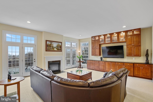 living area featuring recessed lighting, a fireplace with flush hearth, and light colored carpet