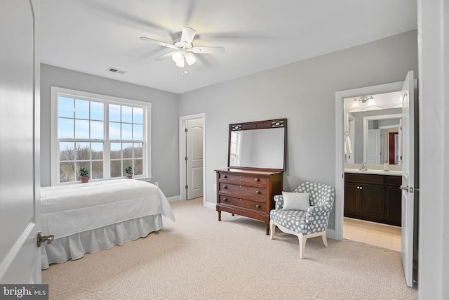 bedroom featuring baseboards, light colored carpet, visible vents, and connected bathroom