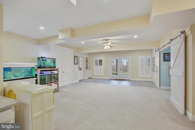 living room with recessed lighting, light colored carpet, baseboards, and a barn door