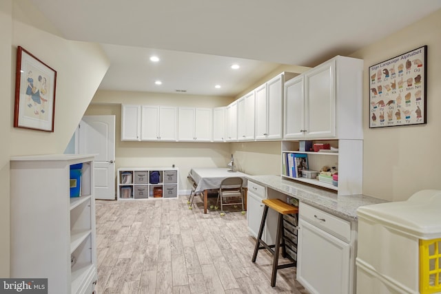 office space featuring recessed lighting, light wood-style floors, visible vents, and built in study area