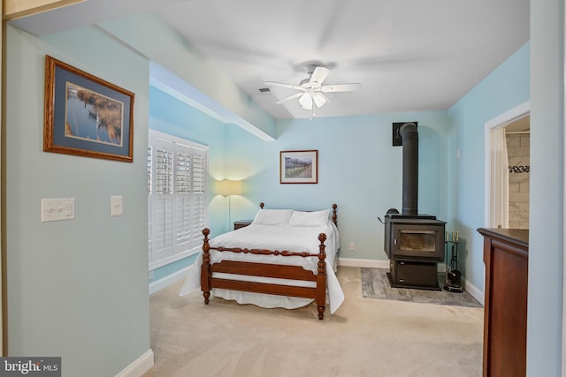 carpeted bedroom featuring ceiling fan, a wood stove, and baseboards