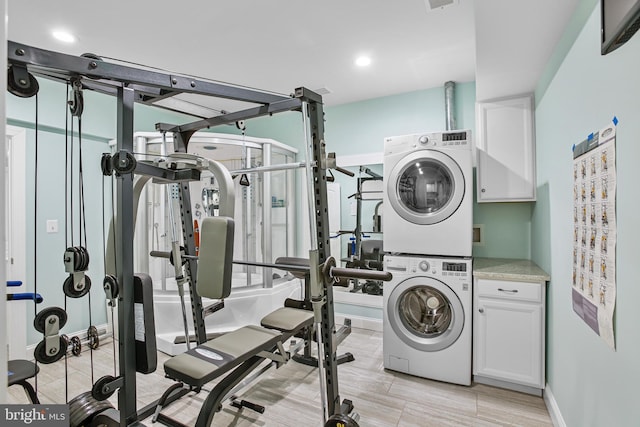 laundry area featuring visible vents, cabinet space, wood tiled floor, and stacked washing maching and dryer