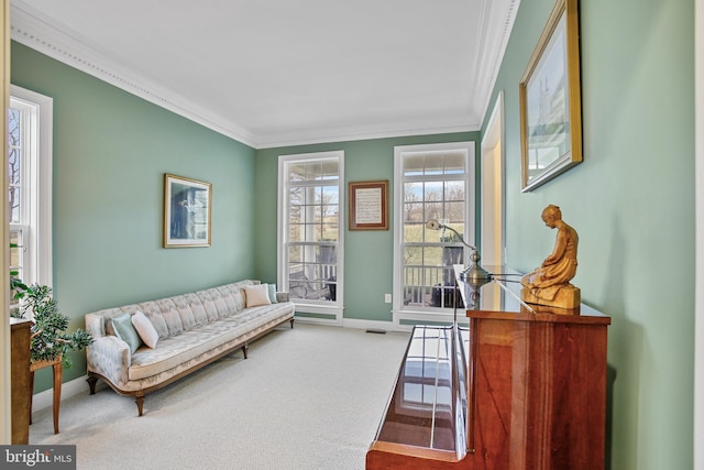 living area with crown molding, carpet, and baseboards