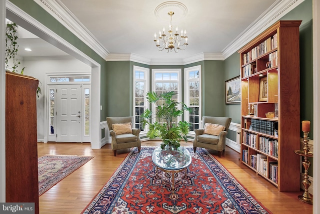 living area with crown molding, a notable chandelier, and wood finished floors