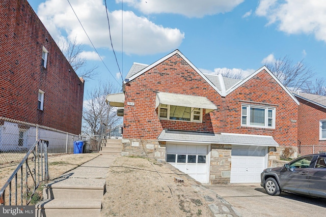 view of front of property featuring brick siding, an attached garage, fence, stone siding, and driveway