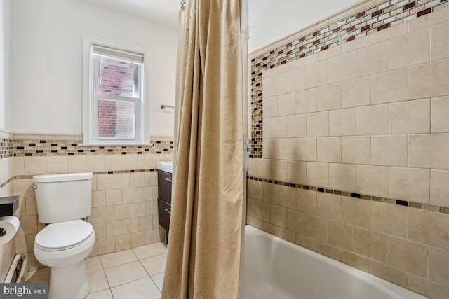 full bath featuring tile patterned flooring, wainscoting, tile walls, toilet, and shower / tub combo with curtain