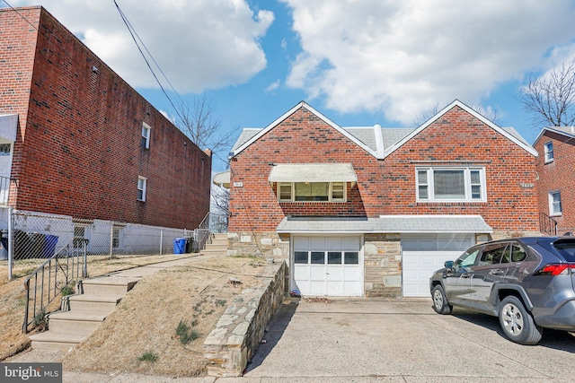 view of front facade featuring fence, driveway, stone siding, a garage, and brick siding