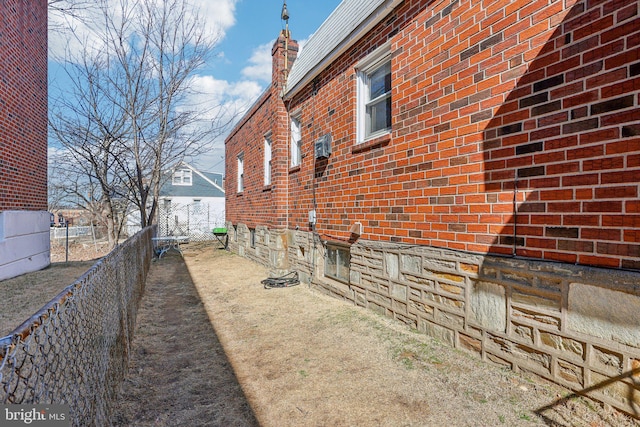 view of home's exterior with fence, brick siding, and a chimney