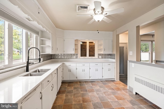 kitchen featuring radiator heating unit, a sink, open shelves, decorative backsplash, and white cabinets