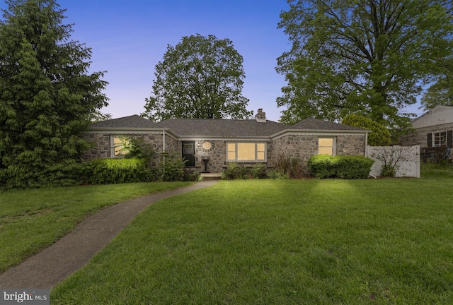 ranch-style home featuring stone siding, a chimney, and a lawn