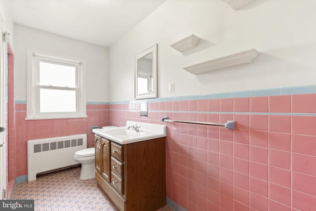 bathroom with radiator, wainscoting, tile walls, plenty of natural light, and vanity