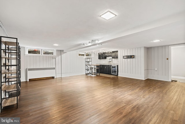 unfurnished living room with radiator heating unit, dark wood-style floors, and wine cooler
