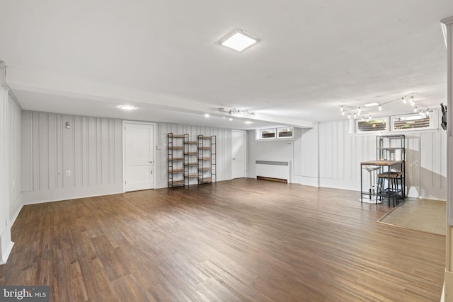 basement with radiator, wood finished floors, and a decorative wall