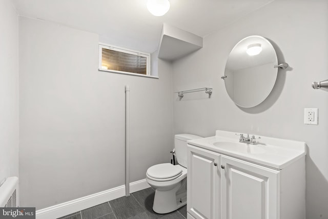 bathroom with toilet, vanity, and baseboards