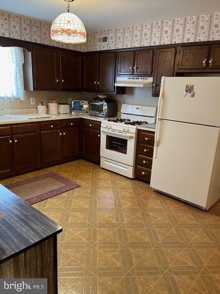 kitchen with under cabinet range hood, white appliances, dark brown cabinets, and wallpapered walls