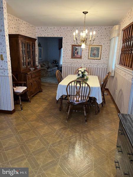 dining room featuring wallpapered walls, baseboards, a wainscoted wall, and a chandelier