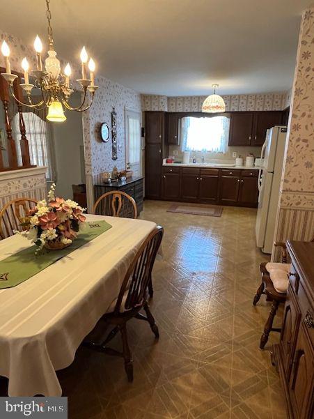 dining area featuring a chandelier and wallpapered walls