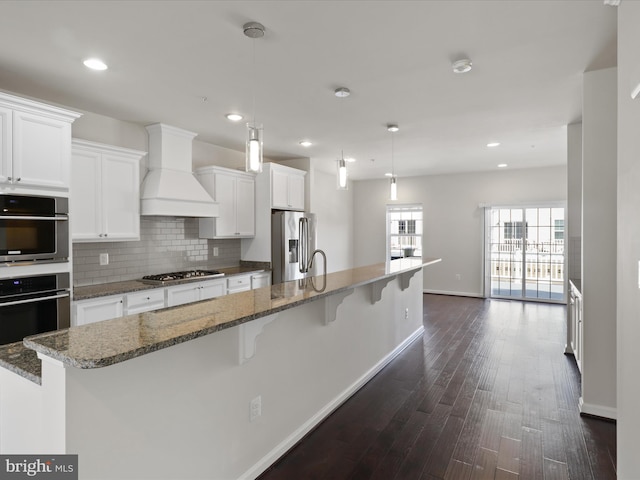 kitchen featuring appliances with stainless steel finishes, white cabinets, custom range hood, and decorative backsplash