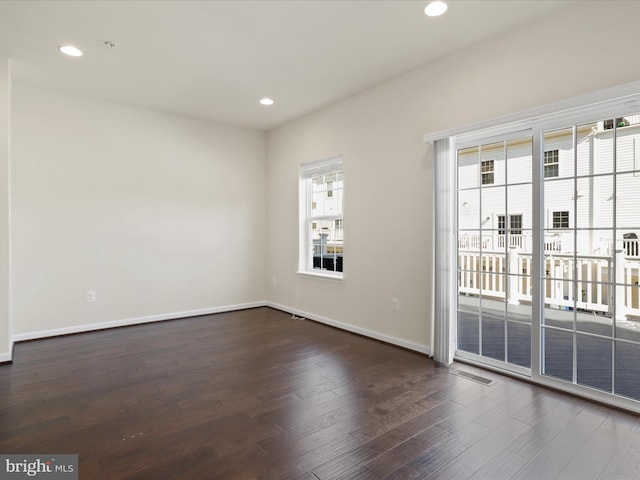 unfurnished room with dark wood-style floors, visible vents, baseboards, and recessed lighting