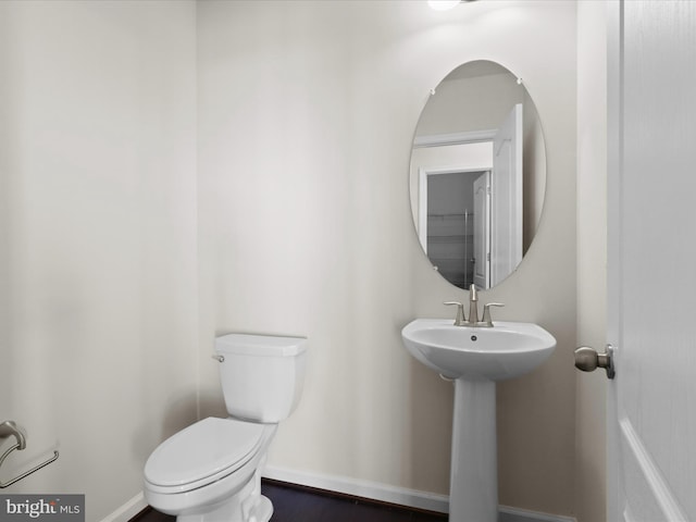 half bath featuring baseboards, a sink, and toilet