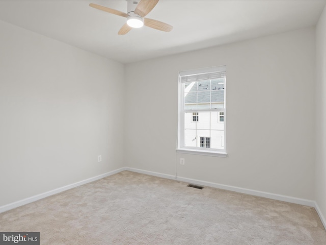 carpeted spare room with ceiling fan, visible vents, and baseboards