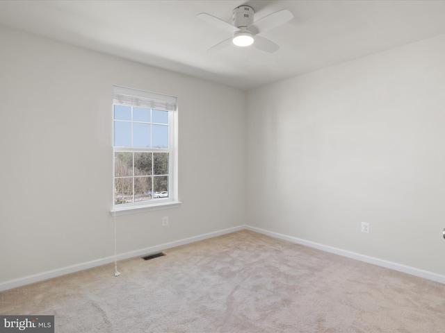 empty room featuring carpet floors, visible vents, ceiling fan, and baseboards