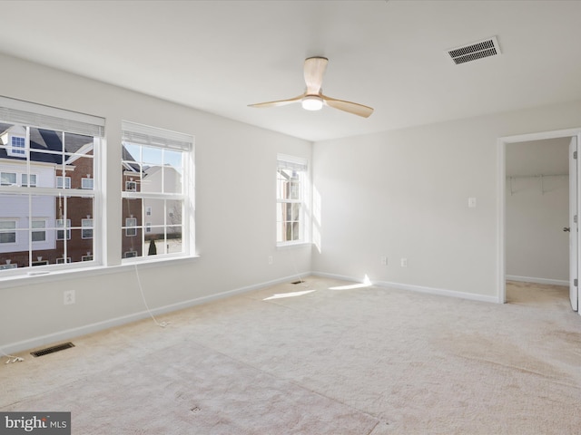 carpeted spare room with visible vents, ceiling fan, and baseboards