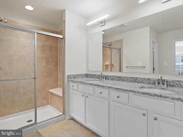 full bath featuring double vanity, a sink, a shower stall, and tile patterned floors