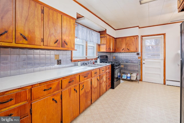 kitchen with a sink, brown cabinetry, light countertops, baseboard heating, and black range with gas cooktop